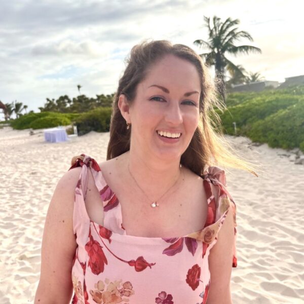 Hilary Baird i ljusrosa blommig klänning på en strand